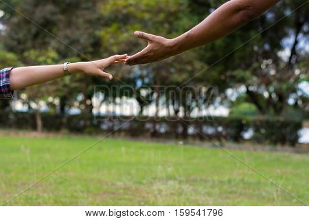 Woman sitting on the grass reaching to shake the hand of man. helping hand and love concept.