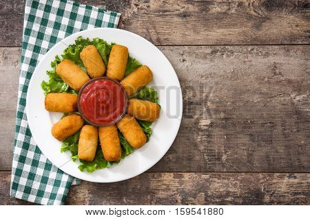 Traditional fried Spanish croquetas (croquettes) with ketchup in plate on wooden background