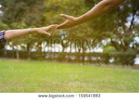 Woman sitting on the grass reaching to shake the hand of man. helping hand and love concept.
