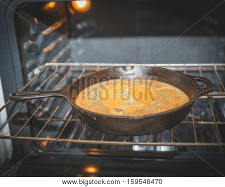 Blue corn bread in a cast iron pan on an oven rack.