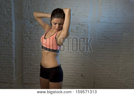 young beautiful and sexy woman in fitness top and shorts with perfect abdomen posing isolated on dim light interior background in healthy lifestyle sport and diet concept