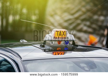 PARIS FRANCE - JULY 14 2011: Taxi Parisien - Paris Taxi sing on the roof of a transportation car in French Captial on a sunny day