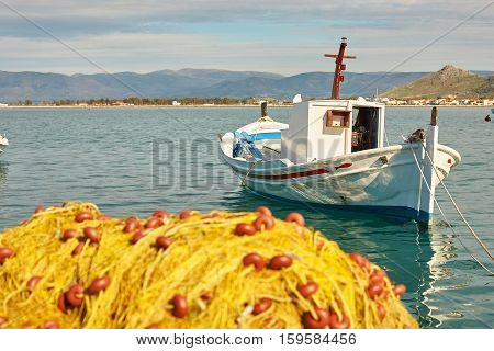 White Boat And Pile Of Yellow Fishing Nets In Port