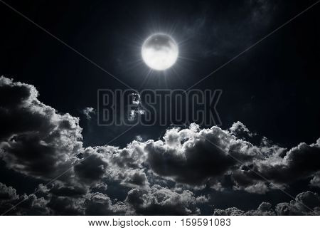 Dramatic photo illustration of a nighttime sky with brightly lit clouds and large. Beautiful starry night sky with clouds and bright full moon or super moon.