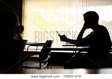Silhouette of seriously middle edge man holding smartphone in meeting room or conference room. Phone with blank screen texting video calls holidays work using internet copy space.