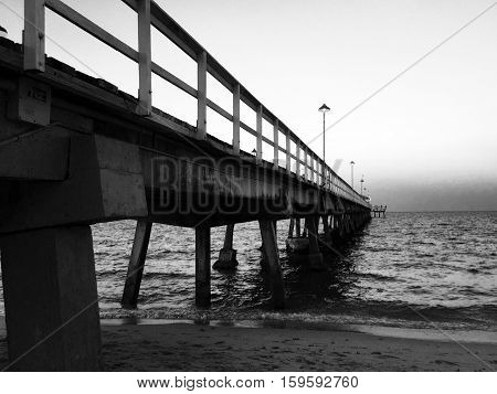 Walkway of the pier along to the ocean in black and white style