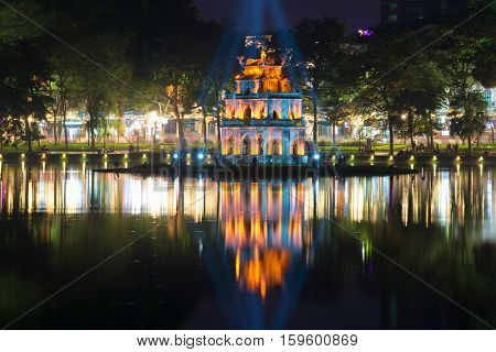 HANOI, VIETNAM - JANUARY 10, 2016: A tower of the Turtle against the background of the city embankment in a night landscape. The religious landmark of the city Hanoi, Vietnam