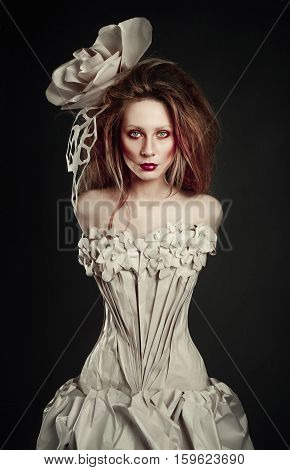 Beautiful redhead girl in elegant paper dress. Sensual image with bright makeup. Beauty model