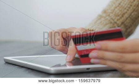 Young woman buying goods from the internet and entering number security code from credit card on digital tablet. Online, technology and internet concept