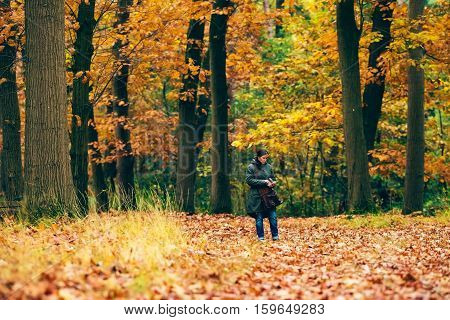 Woman Checking Smartphone On Path In Autumn Forest.