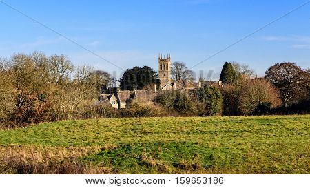 Colerne with Church of St. John the Baptist, Wiltshire. Parish church within a rural English landscape with fields in front of blue clear winter sky