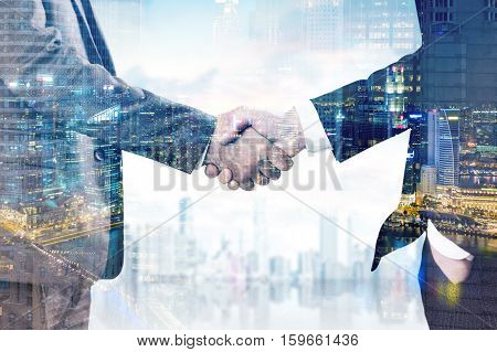 Close up of two businessmen shaking hands. Cityscape is in the background. Night city view is in the foreground. Double exposure