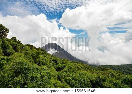 The perfect peak of the active and young Izalco volcano seen from a view point in Cerro Verde National Park in El Salvador. Nearly covered with thick white clouds. Central America