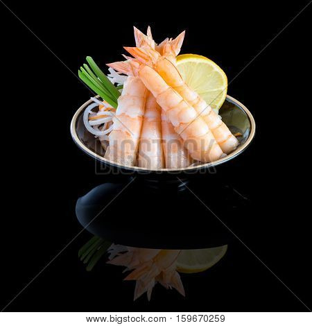sashimi with shrimp in a black plate. On a black background with reflection.