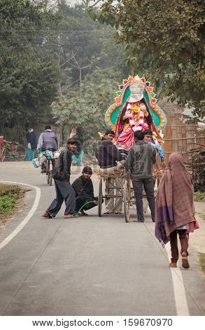 February 3 2014. India. Uttar Pradesh. Young people pump up a wheel at the vehicle in which they carry murti (a sculpture made with help a clay and straw) Sarasvati she has the newspaper which covered the face. They going on Vasant-panchami's holiday. Sar