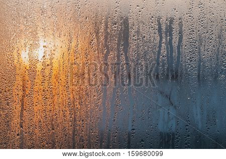 Drops of water on a window glass. Sunrise sky.
