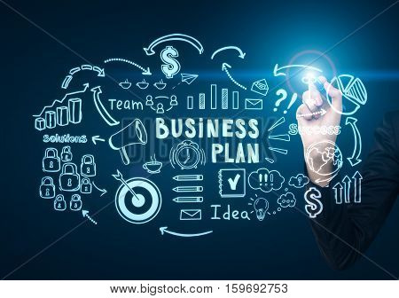 Close up of a businessman's hand drawing a business plan sketch on a glassboard in a dark blue room. Concept of business strategy