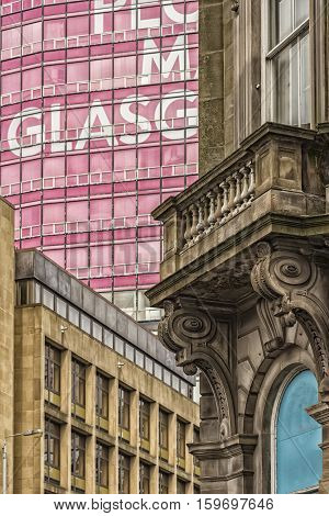 The corner facade of an old sandstone building and the retro style college of building and printing in the background sandwiches a modern building in a scene from the Scottish city of Glasgow.