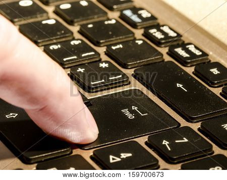close up of a personal computer with italian keyboard with enter command and a finger that is pressing it