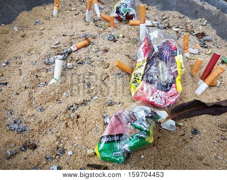 CHIANG RAI THAILAND - NOVEMBER 25: Used cigarette butt in dirty ash tray with sand and crumpled cigarette case on November 25 2016 in Chiang rai Thailand