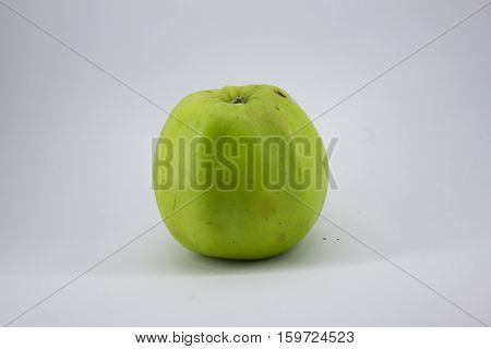 green, juicy, slightly bruised apple on a white background