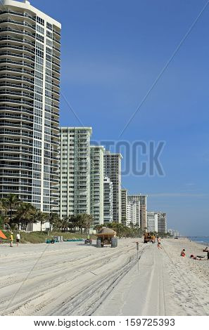 Fort Lauderdale FL USA - March 3 2016: Dump trucks with sand leave beach tracks in beach restoration. Dump trucks with sand pass people to replenish the beach.