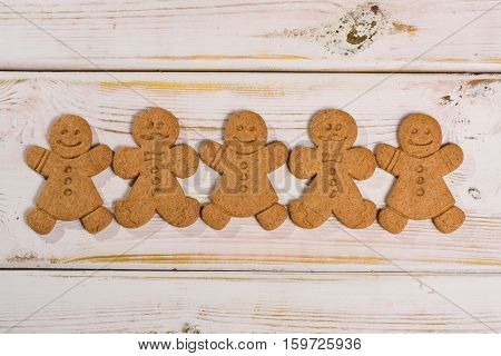 Christmas smiling gingerbread men men and women on rustic wooden background