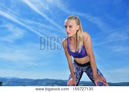 Sweaty fitness woman tired after training. Caucasian female athlete sweating and exhausted after exercising on sky copy space background.
