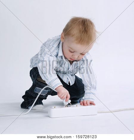 little boy plays with plug on white background
