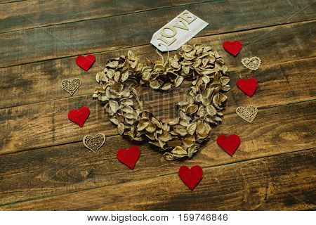 Heart maked with dry petals on a wooden background
