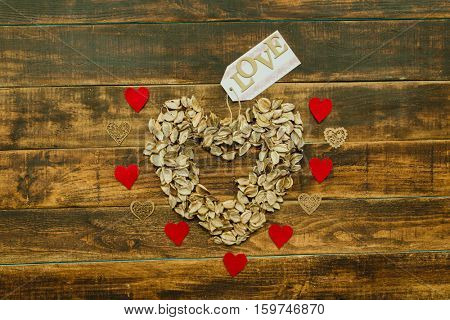 Heart maked with dry petals on a wooden background