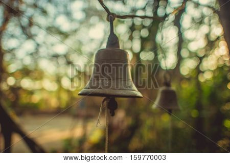 Bronze bells with a rope on a background of trees