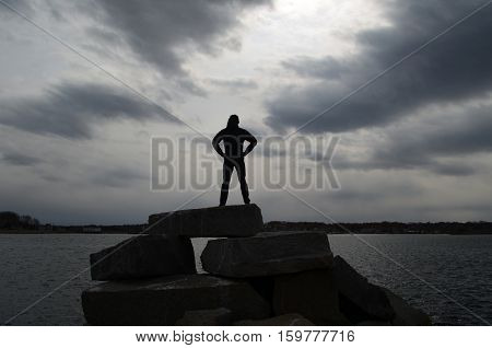 Teen silhouetted on rocks in Scituate on a rock jetty.