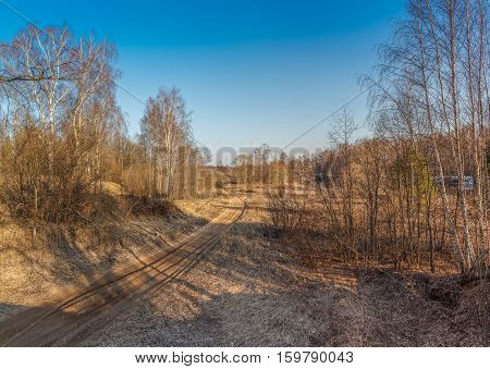 The road through the field in the early spring, the snow has melted, the grass has not grown