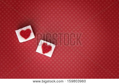 Sugar cubes with a red heart on one of them as background. Top view. Diet unhealty sweet addiction concept