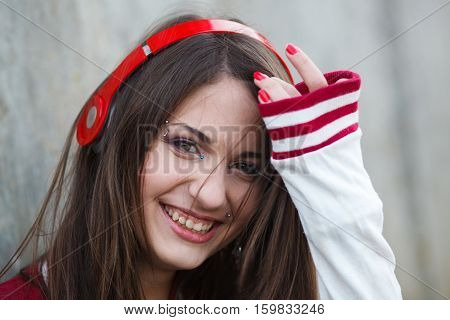beautiful smiling teenager girl with piercing and make up listening music in headphones. Selective focus.