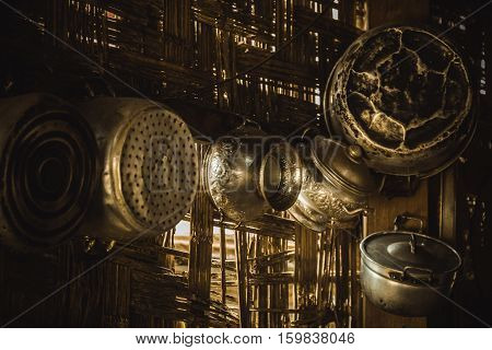 battered old pots and pans hanging on a bamboo wall