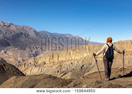 girl with a backpack and trekking poles looks at mountain pass Gyu La, Nepal