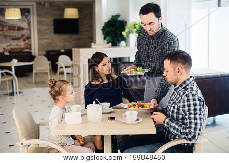 Happy family having breakfast at a restaurant.