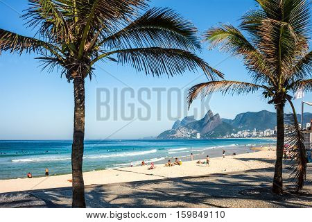 Rio de Janeiro Brazil - July 24 2016: Tourists and active residents are in the Ipanema Beach and front street with palms and mosaic of sidewalk in the sunny morning