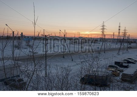 Orange sunset on the winter industrial street. View from window in the frosty evening. Road with cars