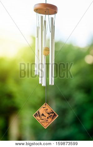 Feng shui chimes with nature in the background with a clear blue sky and defocused tree in the background on a sunny day