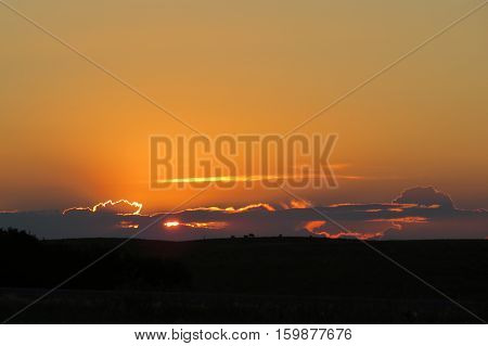 Sunset behind clouds in a Saskatchewan field, Canada.