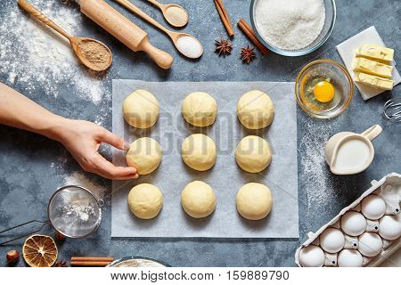 Baker hands preparing dough for buns recipe ingridients food flat lay on kitchen table background. Working with butter, milk, yeast, flour, eggs, sugar pastry or bakery cooking. Top view