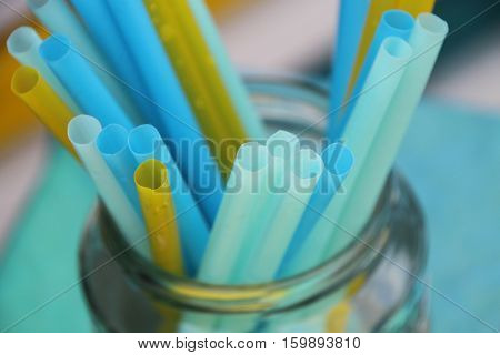 Colorful blue and yellow drinking straws for beverages in jar