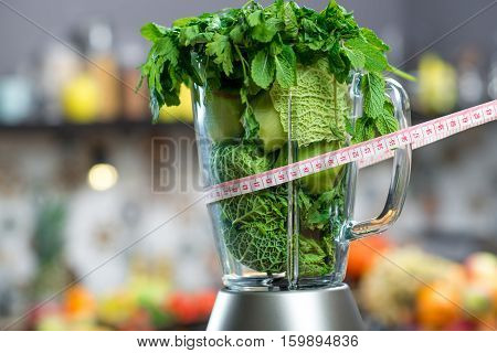 Close up view on the blender full of green fruits and vegetables ready to mix with meter in the kitchen. Healthy vegetarian diet for weight loss and detox