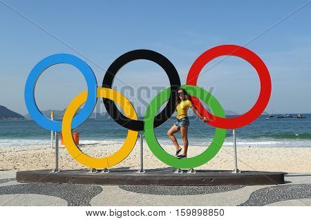 RIO DE JANEIRO, BRAZIL - AUGUST 6, 2016: Brazilian tourist taking picture of Olympic Rings at Copacabana Beach in Rio de Janeiro