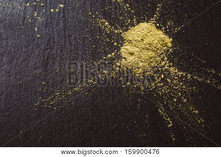 Powdered matcha green tea on black stone surface. Traditional Japanese and tea matcha