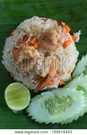 A simple menu of stir-fried rice with prawns and vegetables served on a banana leaf.