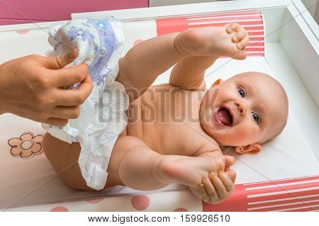 Mother Changing Diaper To Her Little Baby Girl
